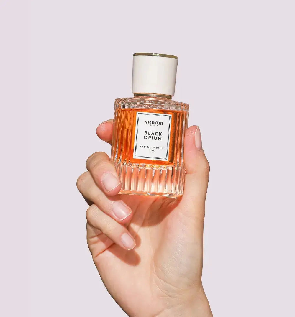 Hand holding a bottle of Black Opium perfume.