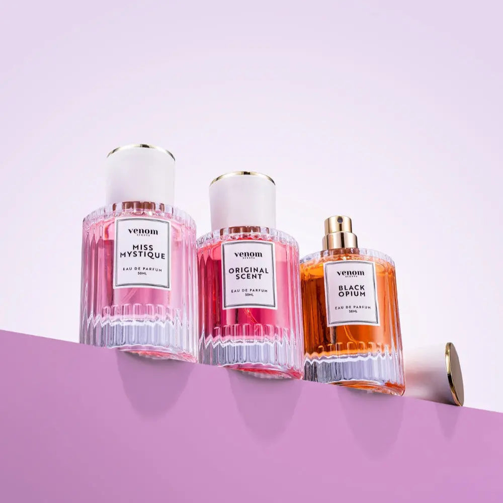 Three perfume bottles labeled Miss Mystique, Original Scent, and Black Opium on a pink background.